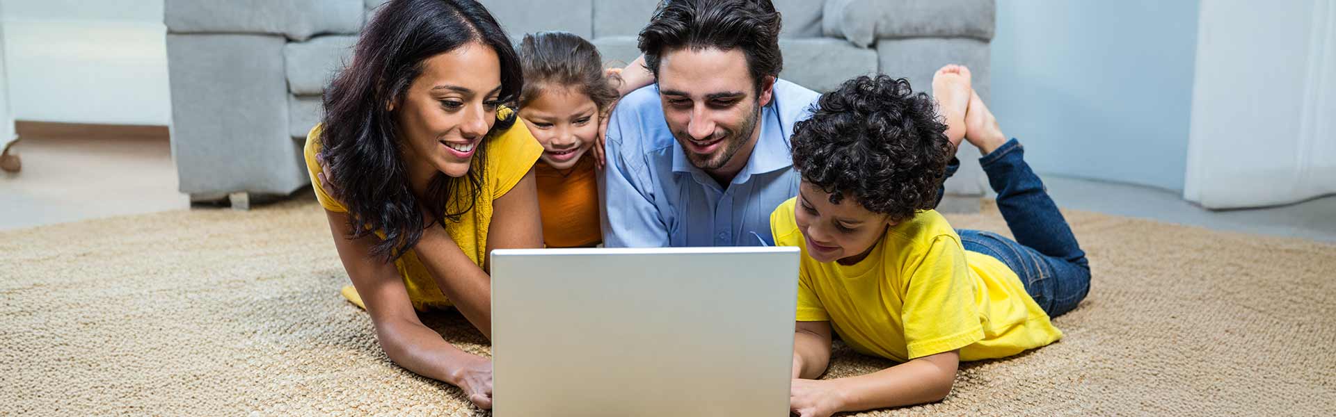 A family in the floor looking at a laptop